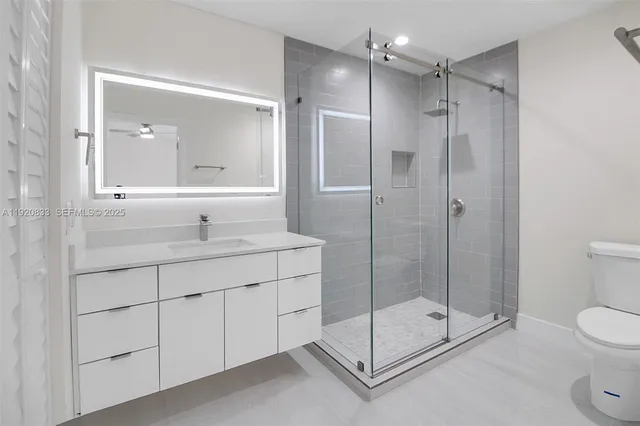 a bathroom with a shower sink mirror and toilet