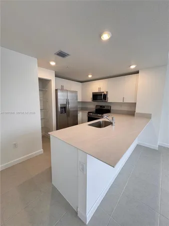 a large kitchen with kitchen island a sink stainless steel appliances and cabinets