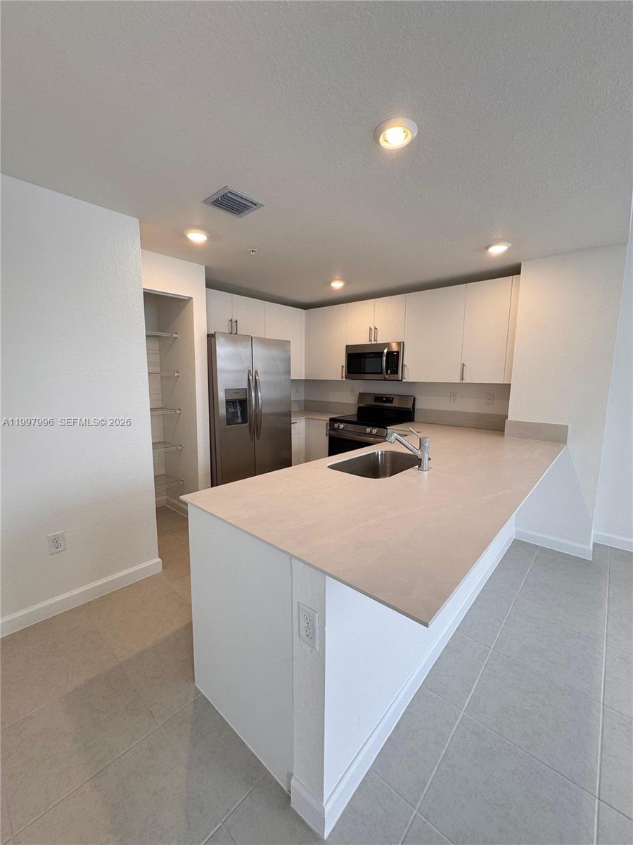 15615 Southwest 280th Street, Unit 10 Homestead, FL 33032 - Photo 5 of 23 a large kitchen with kitchen island a sink stainless steel appliances and cabinets