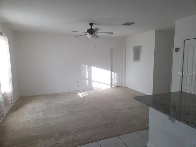 an empty room with windows and chandelier fan
