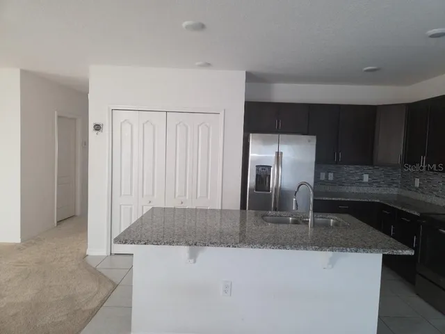 a kitchen with stainless steel appliances granite countertop a sink a stove and a refrigerator