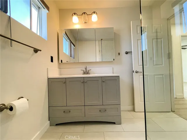 a bathroom with a granite countertop sink a mirror and shower