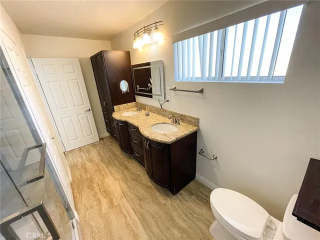 a bathroom with a granite countertop sink toilet and mirror