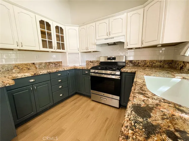 a kitchen with stainless steel appliances granite countertop a stove a sink and a microwave