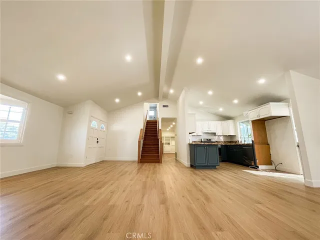 a view of a kitchen with kitchen island wooden floors wooden cabinets counter space and stainless steel appliances