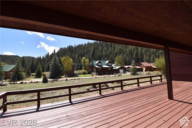1129 Ponderosa Road, Unit 40 Hatch, UT 84735 - Photo 41 of 47 Expansive wood-finish deck with a rustic railing, offering open-air seating and a backdrop of dense evergreen trees