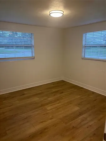 a view of an empty room with wooden floor and a window