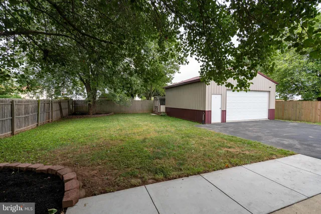 a view of a small house with a small yard and a large tree