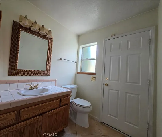 a bathroom with a toilet a sink a mirror a vanity and window