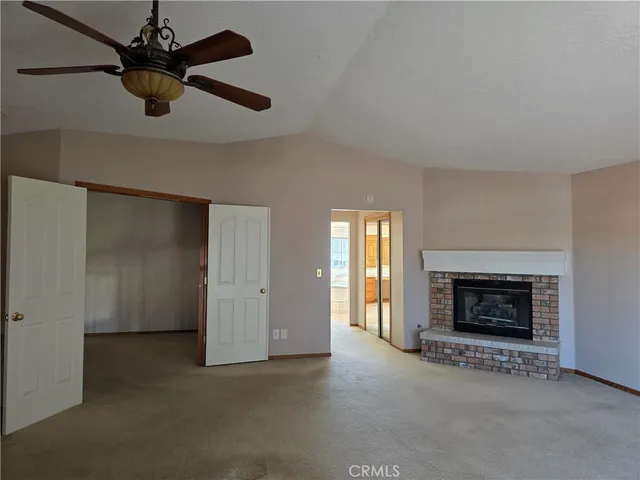 an empty room with ceiling fan and fireplace