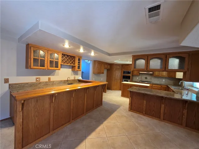 a large kitchen with stainless steel appliances wooden cabinets and a sink