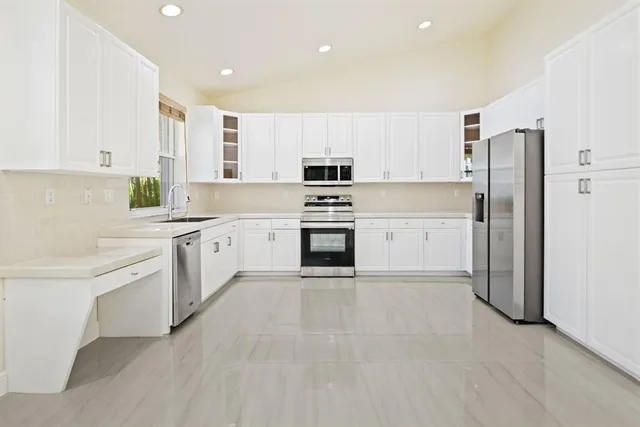 a kitchen with white cabinets and stainless steel appliances