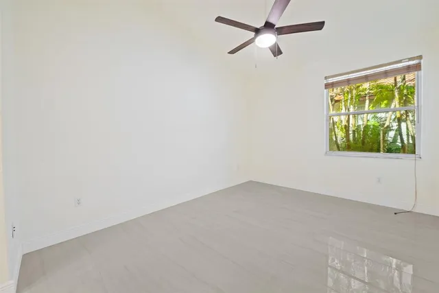 an empty room with windows and fan