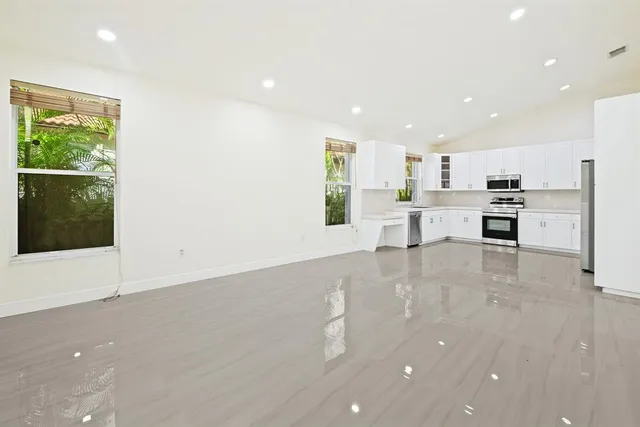 a large kitchen with stainless steel appliances a large counter top a stove and a refrigerator