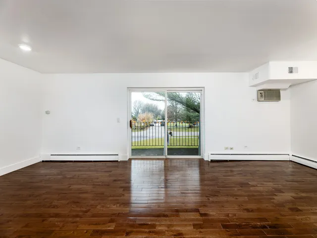 a view of empty room with wooden floor and floor to ceiling window