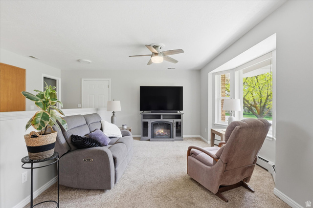 45 West 100 South Mendon, UT 84325 - Photo 8 of 64 Living room featuring a glass covered fireplace, ceiling fan, light carpet, and baseboard heating