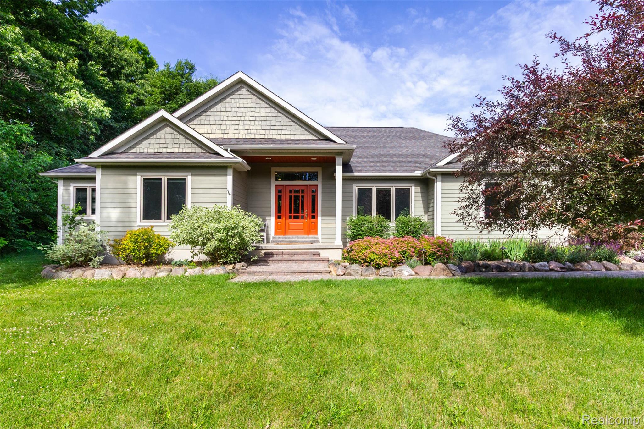 Ranch-style residence featuring light green siding, a prominent dark orange front door, and a gray shingled roof