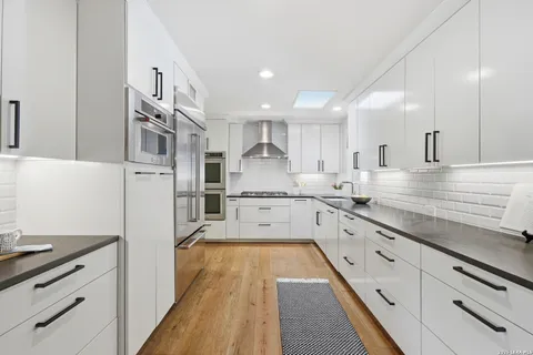 a large kitchen with stainless steel appliances lots of counter space and wooden floor