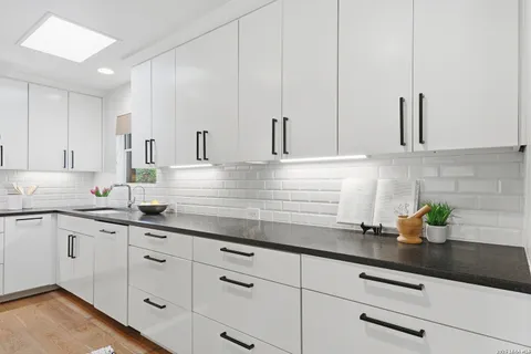 a kitchen with white cabinets a sink and dishwasher with white cabinets