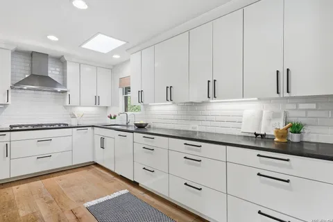 a kitchen with granite countertop white cabinets and white stainless steel appliances