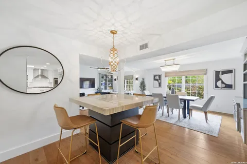 a dining room with wooden floor a chandelier a wooden table and chairs