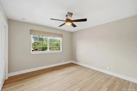 an empty room with wooden floor ceiling fan and window