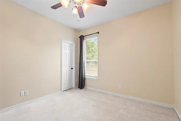 an empty room with a chandelier fan and windows