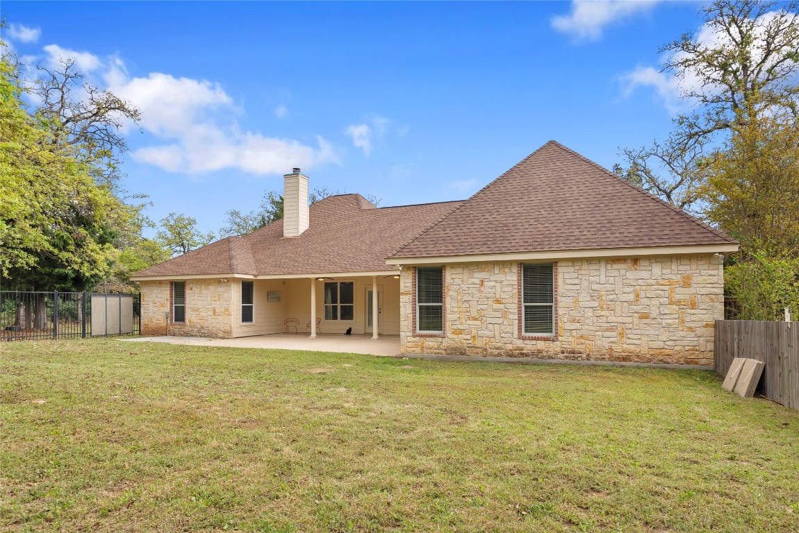 330 Arbors Circle Elgin, TX 78621 - Photo 29 of 39 Back of house featuring stone siding, a fenced backyard, a lawn, and a patio area