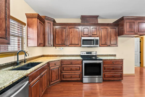 a kitchen with stainless steel appliances granite countertop wooden floors and cabinets