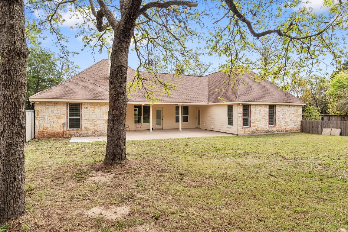 330 Arbors Circle Elgin, TX 78621 - Photo 32 of 39 Back of house with fence, a patio, stone siding, a shingled roof, and a yard