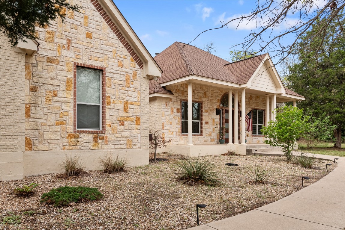 330 Arbors Circle Elgin, TX 78621 - Photo 34 of 39 View of side of home with stone siding, a shingled roof, and covered porch