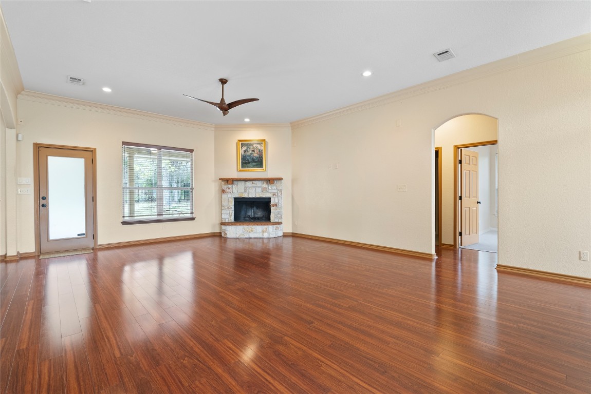 330 Arbors Circle Elgin, TX 78621 - Photo 9 of 39 Unfurnished living room featuring visible vents, a fireplace, ceiling fan, wood finished floors, and arched walkways plus fireplace