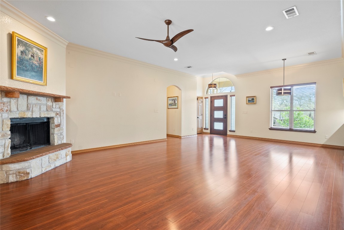 330 Arbors Circle Elgin, TX 78621 - Photo 10 of 39 Unfurnished living room featuring a stone fireplace, visible vents, crown molding, and wood finished floors