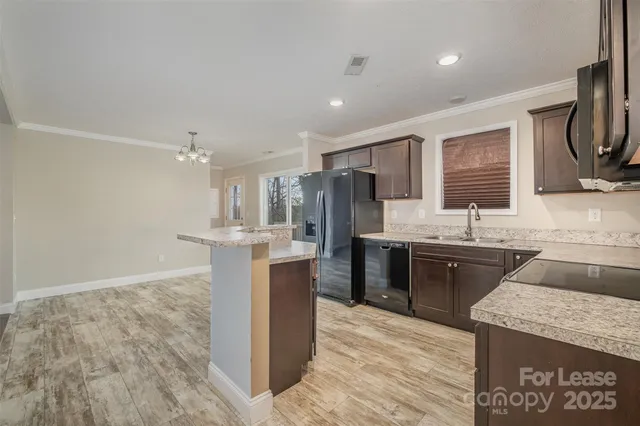 a large kitchen with a sink a refrigerator and a stove top oven with wooden floor