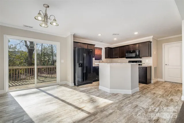 a kitchen with stainless steel appliances kitchen island granite countertop a refrigerator oven a sink with dishwasher a stove and a refrigerator with wooden floor