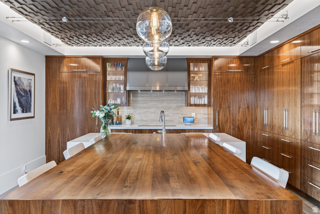 12308 Mariah Circle Draper, UT 84020 - Photo 39 of 293 Expansive walnut wood-finish kitchen island with seating, complemented by a textured ceiling installation and three spherical pendant lights