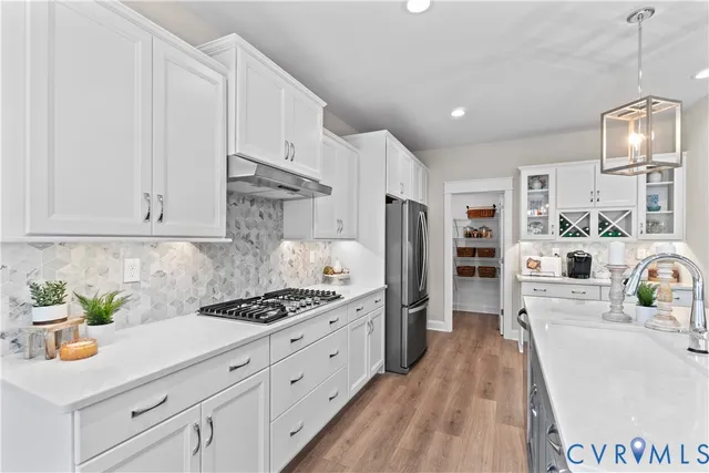 a kitchen with stainless steel appliances granite countertop a refrigerator sink and white cabinets