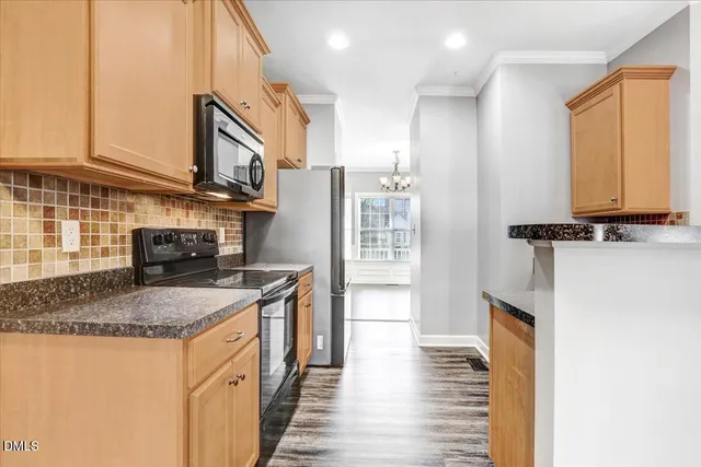 a kitchen with stainless steel appliances granite countertop a stove top oven a sink dishwasher and a microwave oven with wooden floor