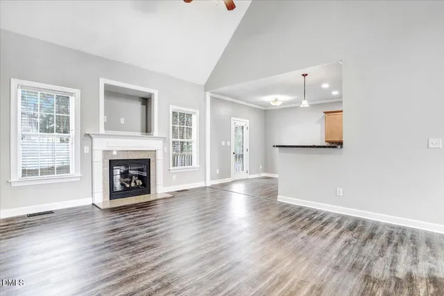 a view of a kitchen and an empty room with wooden floor