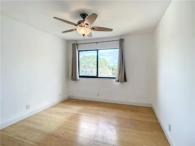 an empty room with wooden floor chandelier and windows