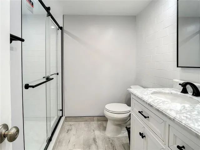 a bathroom with a granite countertop sink toilet and shower