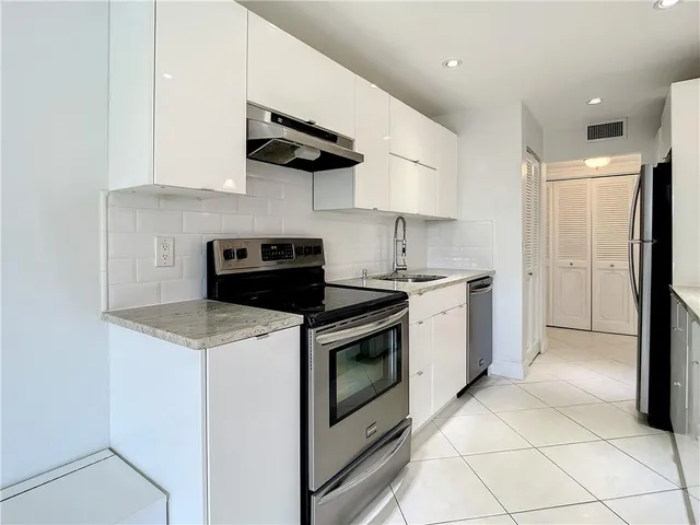 a kitchen with stainless steel appliances granite countertop a sink a stove a refrigerator and cabinets