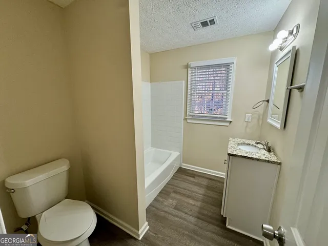 a bathroom with a granite countertop toilet sink and mirror