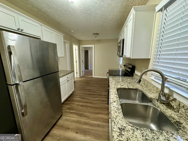 a kitchen with granite countertop a refrigerator and a sink