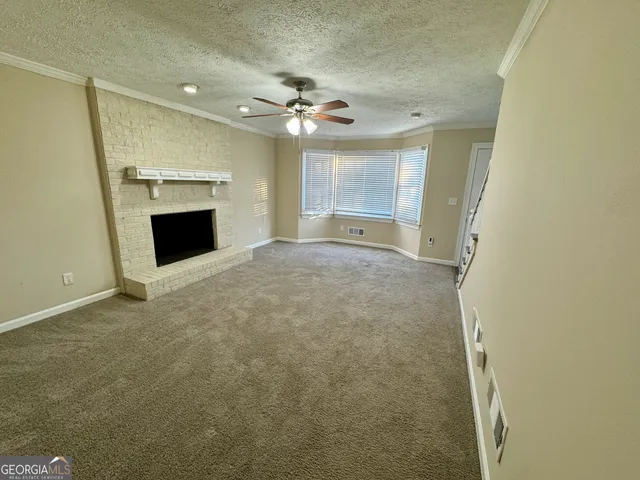 an empty room with a fireplace and a ceiling fan