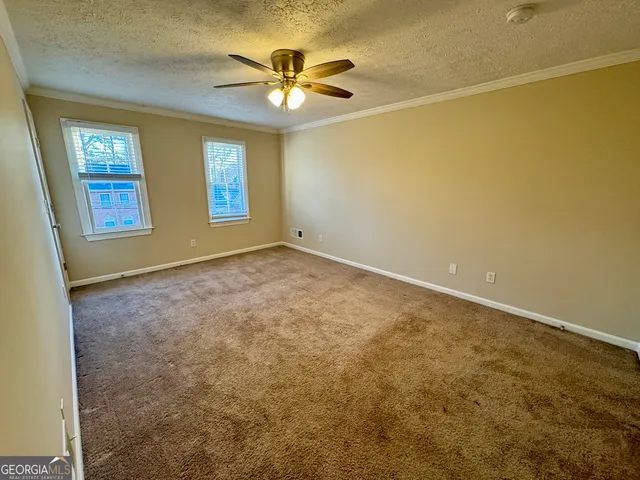 an empty room with windows and ceiling fan