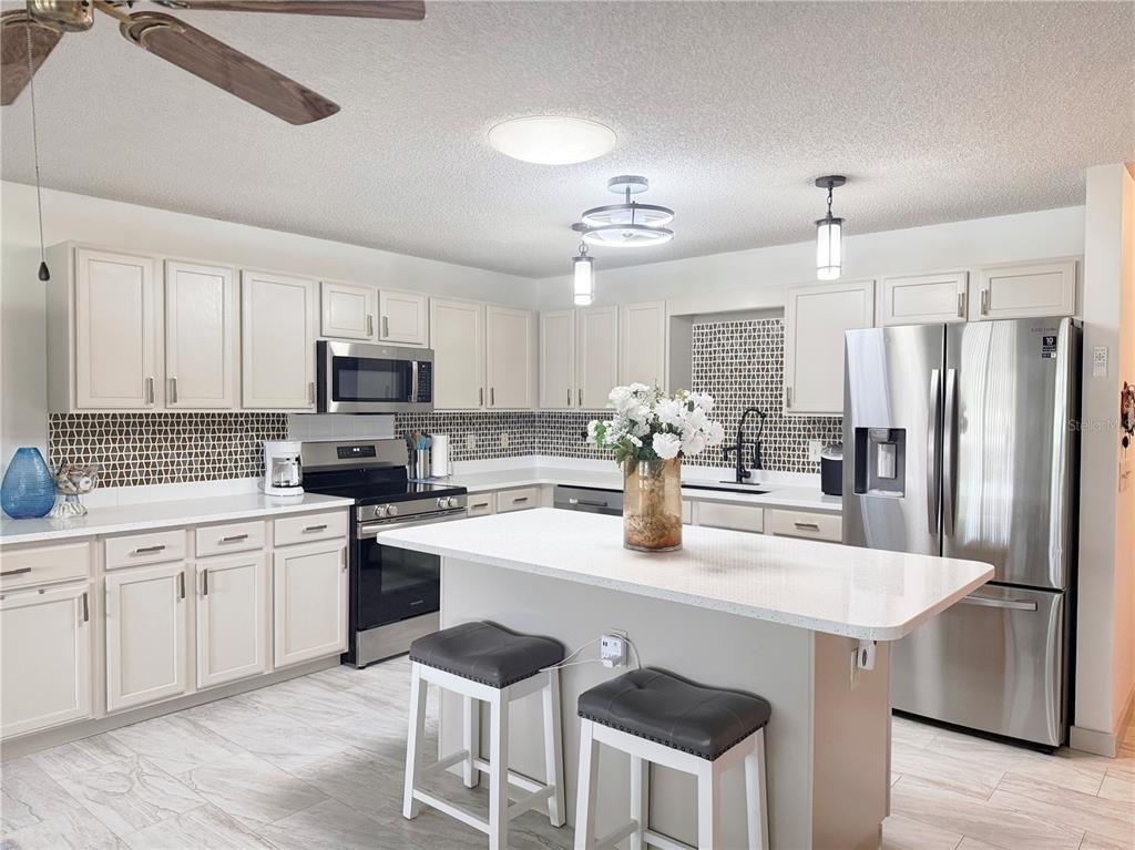 9394 Southwest 97th Lane, Unit A Ocala, FL 34481 - Photo 8 of 22 a kitchen with stainless steel appliances granite countertop a sink a stove a refrigerator cabinets and chairs