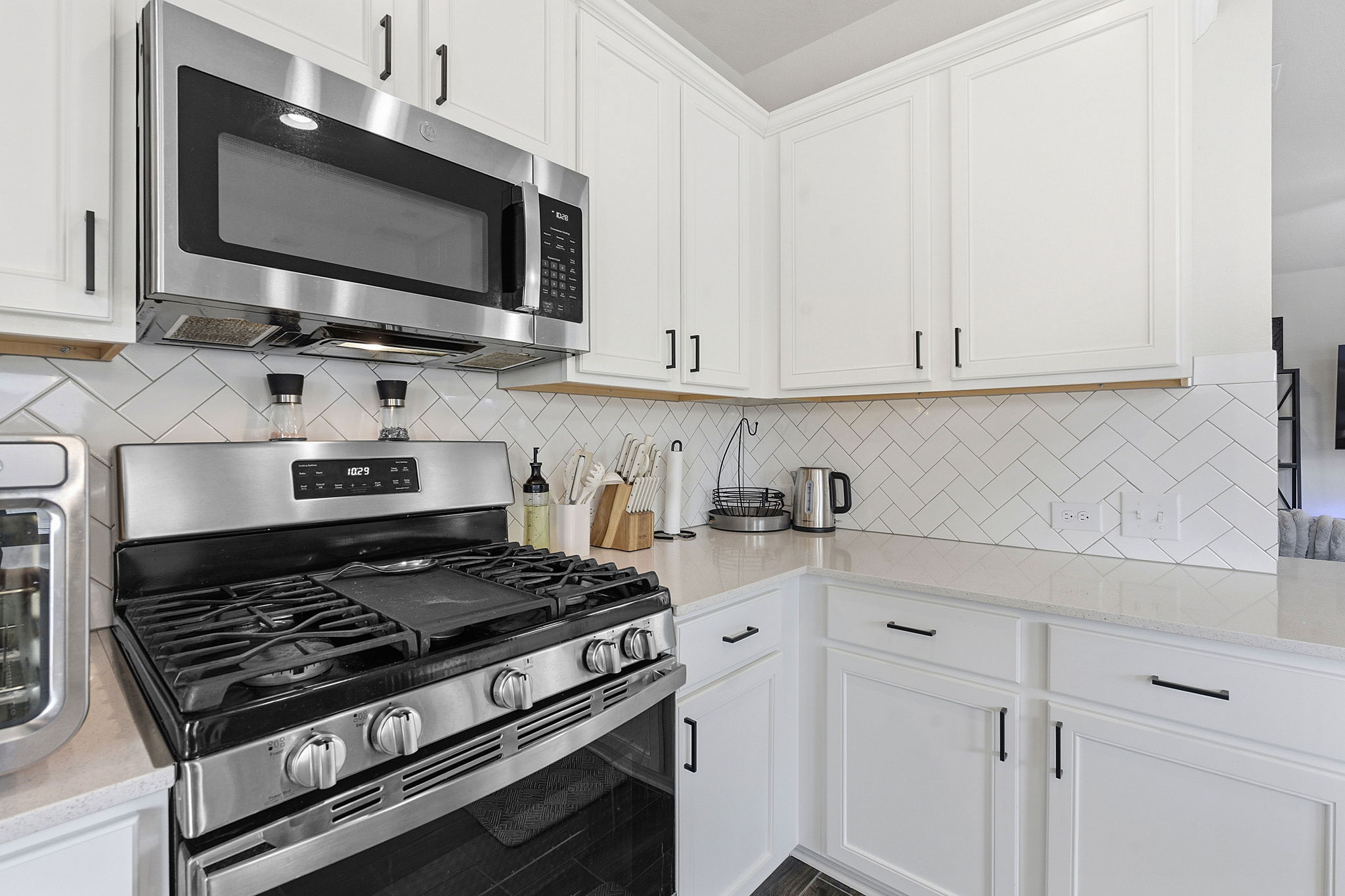12413 Ostrich Trail Manor, TX 78653 - Photo 14 of 29 Kitchen with stainless steel appliances, white cabinetry, light stone counters, and backsplash