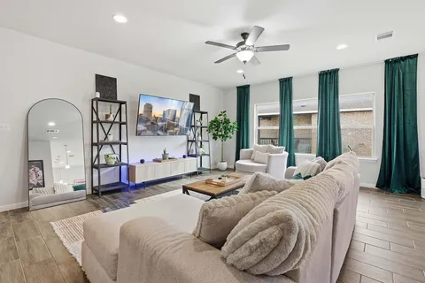 a living room with furniture large window and wooden floor