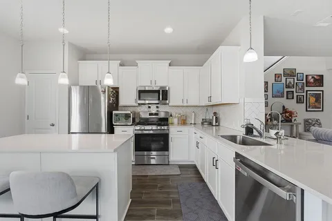 a kitchen with stainless steel appliances granite countertop a sink refrigerator stove and microwave